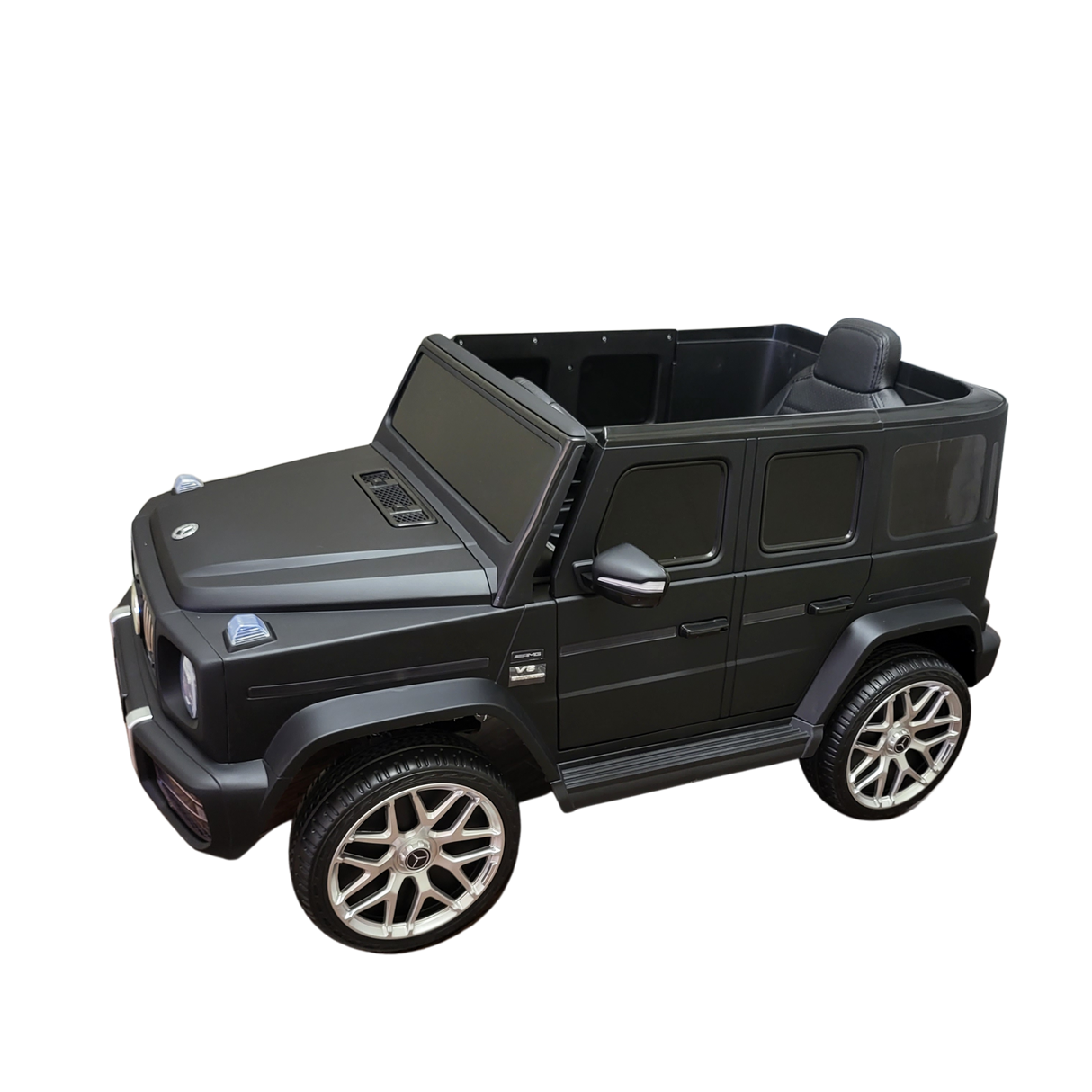 A Limited 12V Matte Edition Mercedes Benz AMG G63 ride-on SUV for kids, in black with silver wheels and detailed grille. The open interior displays upgraded tech, set against a plain backdrop.