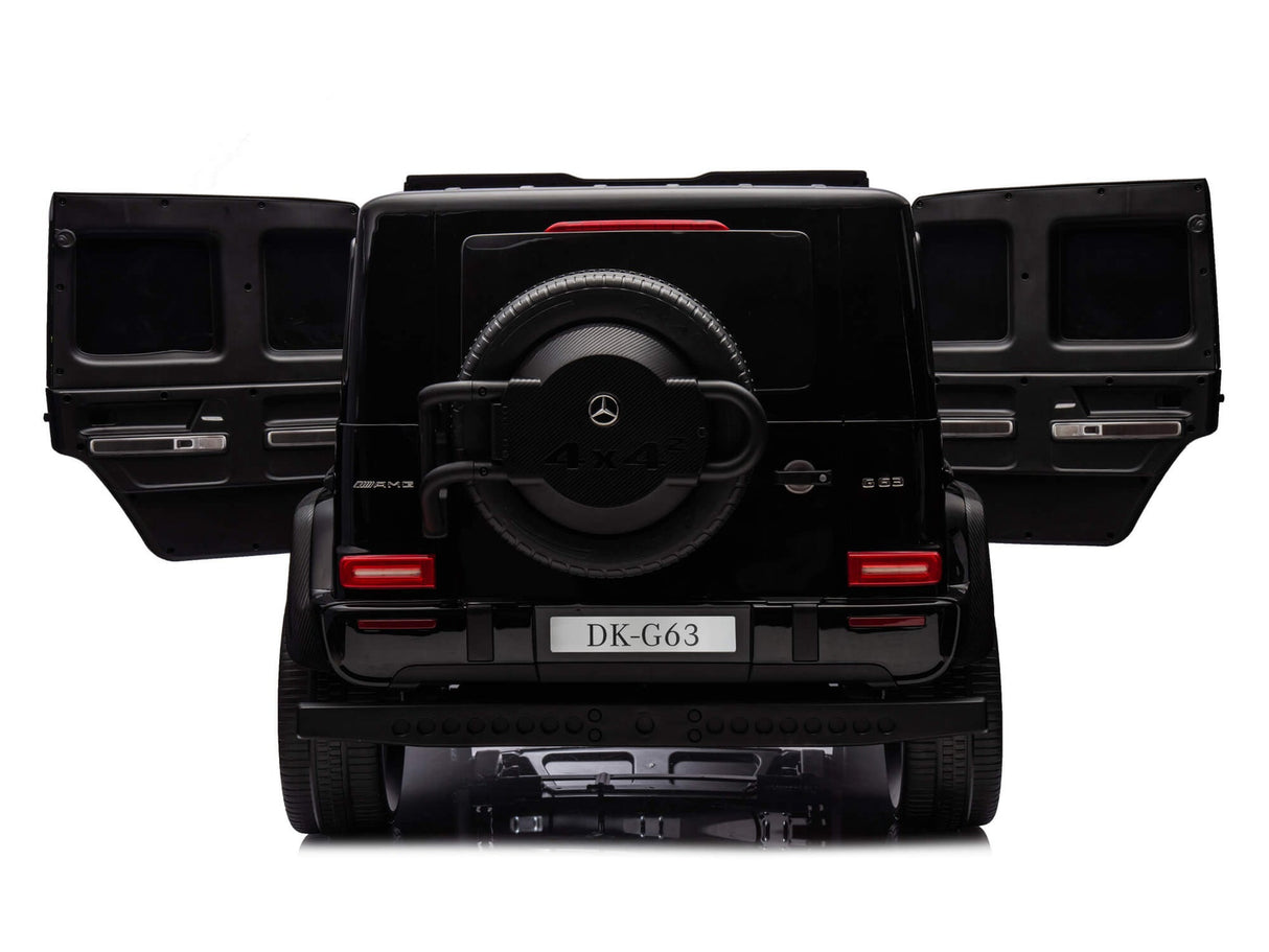 A black Mercedes G63 XXL 24V Kids Ride-On Truck – Platinum Edition is seen from the rear with both doors open, resembling the luxurious SUV. It has a spare tire on the rear door and a DK-G63 plate, featuring dual batteries, 4WD, EVA tires, leather seats, and an MP4 player.