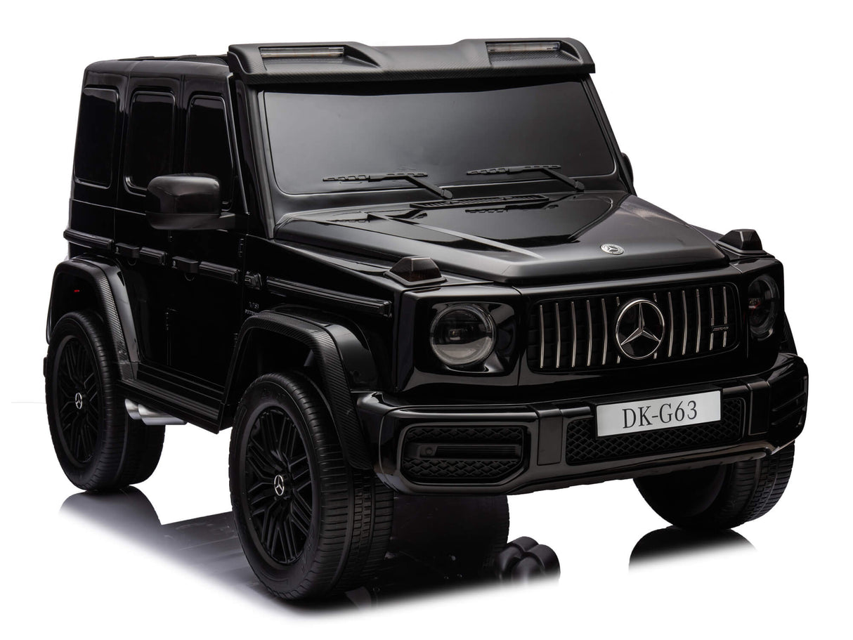 A toy model of the Black Mercedes G63 XXL 24V Kids Ride-On Truck – Platinum Edition is displayed on a reflective surface, highlighting detailed features like the grille, headlights, side mirrors, and DK-G63 front license plate area. It embodies the essence of this 4WD ride-on with MP4 and leather seats.