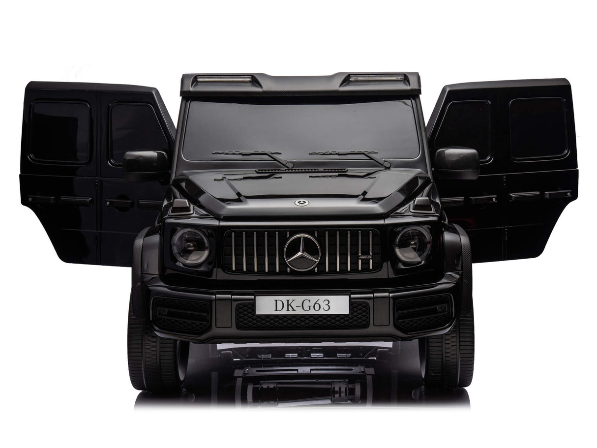 A black Mercedes G63 XXL 24V Kids Ride-On Truck – Platinum Edition with MP4, dual batteries, 4WD, EVA tires, and leather seats is shown from the front with open doors. The grille, headlights, and a DK-G63 license plate are visible on this reflective surface.