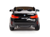 A rear view of the Black 12V Licensed XXL BMW X6 Ride On Car against a white background showcases its dual exhaust pipes and red taillights. Ideal as a 2-seater ride, its license plate reads BMW X6M.