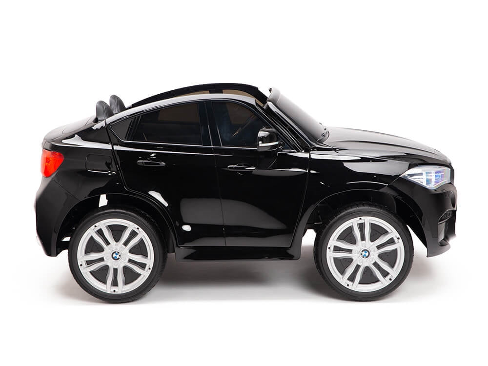 The Black 12V Licensed XXL BMW X6 Ride On Car with Remote Control is styled as a luxury SUV, featuring glossy black paint and silver wheels, detailed side features like realistic glass windows and side mirrors, delivering an authentic driving experience for young adventurers.