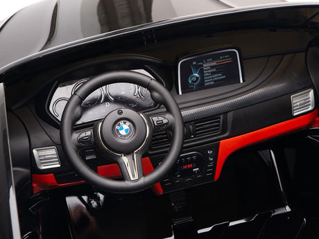 The Black 12V Licensed XXL BMW X6 Ride On Car boasts a sleek, modern interior with a steering wheel, red-accented dashboard, and digital display. This remote-control car delivers an authentic driving experience for kids with multiple dials.