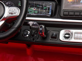 A close-up of the Red 2x24V/4WD Platinum XXL Mercedes G63 Ride On Truck dashboard reveals a black and red gear lever marked D, remote control, start/stop button, navigation screen with map, various controls, circular air vent, and part of the steering wheel.