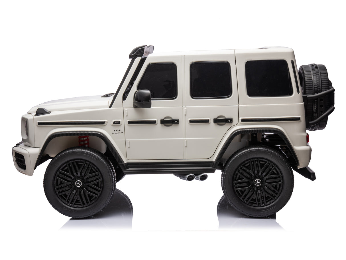 The White 2x24V/4WD Platinum XXL Mercedes G63 Ride On Truck features a boxy shape, large black EVA wheels, tinted windows, and a rear spare tire. Its 4-wheel drive adds excitement to the sleek design with MP4 and leather seats against a white background.