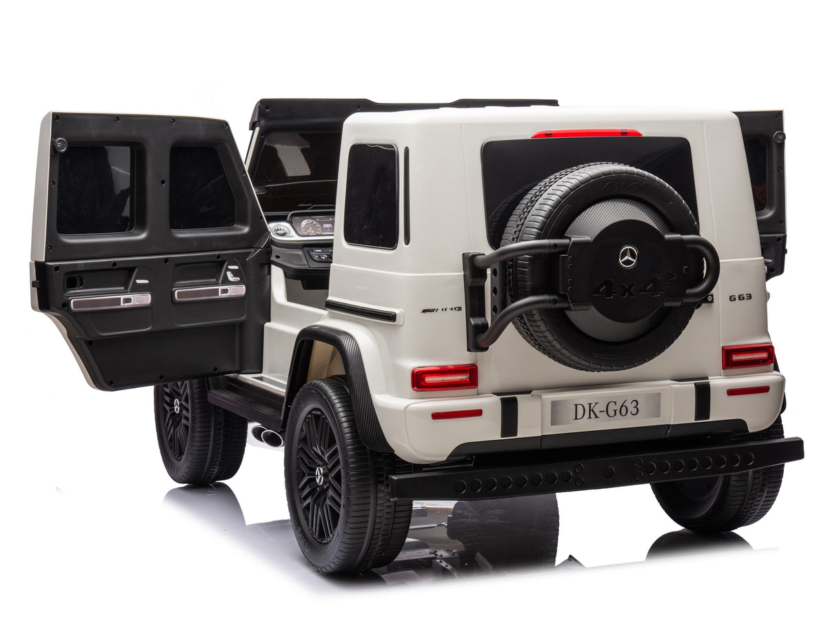 The White 2x24V/4WD Platinum XXL Mercedes G63 Ride On Truck features rear tire 4x4 detail, an open interior with leather seats, license plate DK-G63, and remote control access for a thrilling drive. Its displayed on a reflective surface.