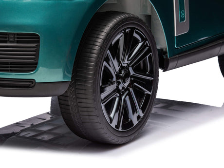 Close-up of a glossy black wheel on the Green Metallic 24V Kids Range Rover luxury ride-on SUV. The tire is sleek, and the deep emerald body shines. The focus is on the rear design, highlighting its detailed luxury car imitation.
.