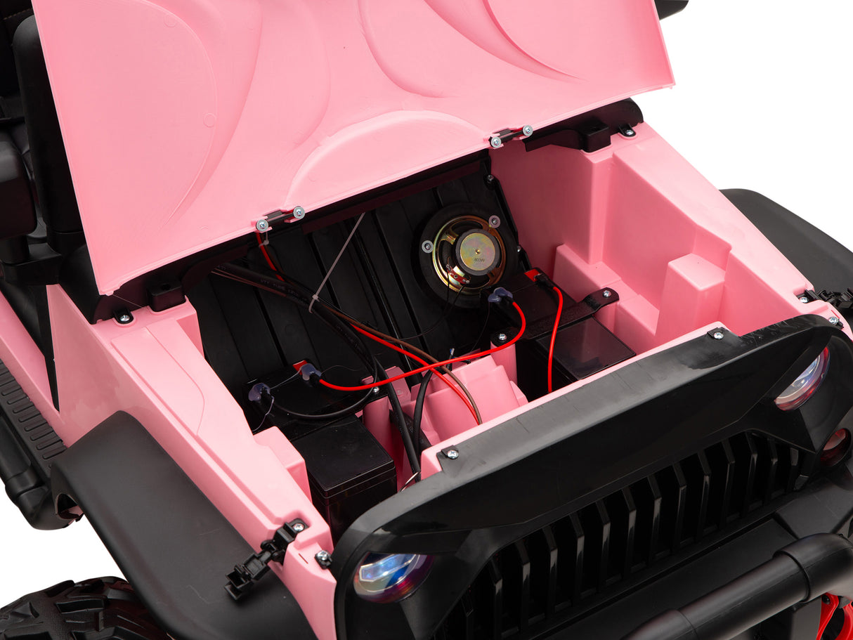 The image shows the open hood of a Pink 24V EVA Big Wheels Kids 1 Seater Upgraded Ride On Truck, revealing its internal components. Visible are a speaker, red and black wires connected to the 24V battery compartment, with features like rubber wheels, remote control, black front bumper, and headlights.