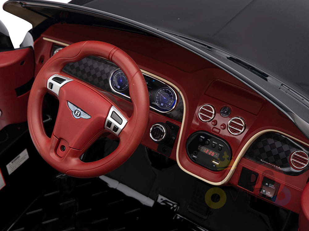 The Black 12V Bentley GTC Kids Licensed Ride On Car features a toy car interior with a red steering wheel, dashboard, two blue-lit gauges, control buttons, and an imitation luxury logo on the wheel. Its styled like the Bentley Sport GT in black and red and includes rubber wheels and a remote control.
