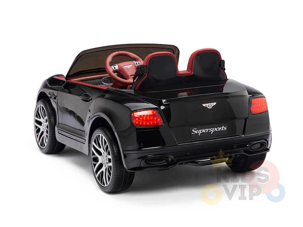 The Black 12V Bentley GTC Kids Licensed Ride-On Car, featuring rubber wheels and a remote, boasts Supersports branding, realistic wheels, and rear lights. With its striking red steering wheel set against a sleek white background, its every childs dream convertible.