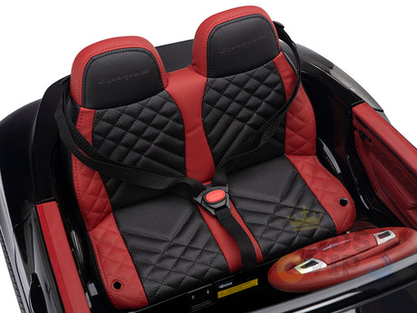 A close-up of the Black 12V Bentley GTC Kids Licensed Ride On Car shows two-tone black and red leather seats with diamond stitching and harness seatbelts. The steering wheel shares this style, adding elegance to the ride-on toy cars design.