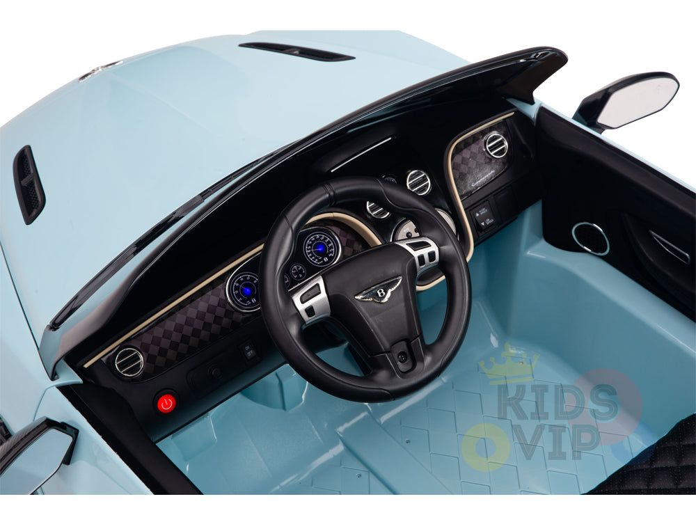 A top view reveals the Blue 12V Bentley GTC Kids Licensed Ride On Cars interior, showcasing a detailed steering wheel, illuminated dashboard controls, start button, leather seat, and textured floor. Luxury details include the Kids VIP logo and rubber wheels.
