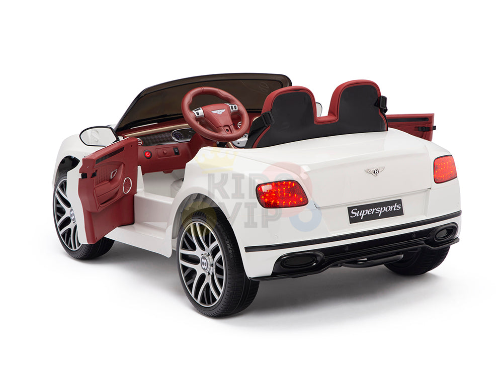The White 12V Bentley GTC Kids Licensed Ride On Car features a sleek white exterior, maroon interior, leather seat comfort, an opening driver-side door, realistic dashboard, side mirrors, and two seats. The rear license plate area displays Supersports. It comes with remote control and rubber wheels.