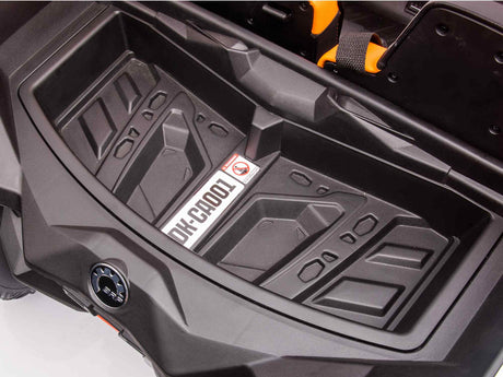 The close-up of a Red 2x24V/2WD Official Can-Am Maverick Ride on Buggys front cargo compartment shows a textured base and warning label, featuring rugged geometric patterns with orange accents, hinting at the powerful LX Performance suitable for adventurous buggy enthusiasts.