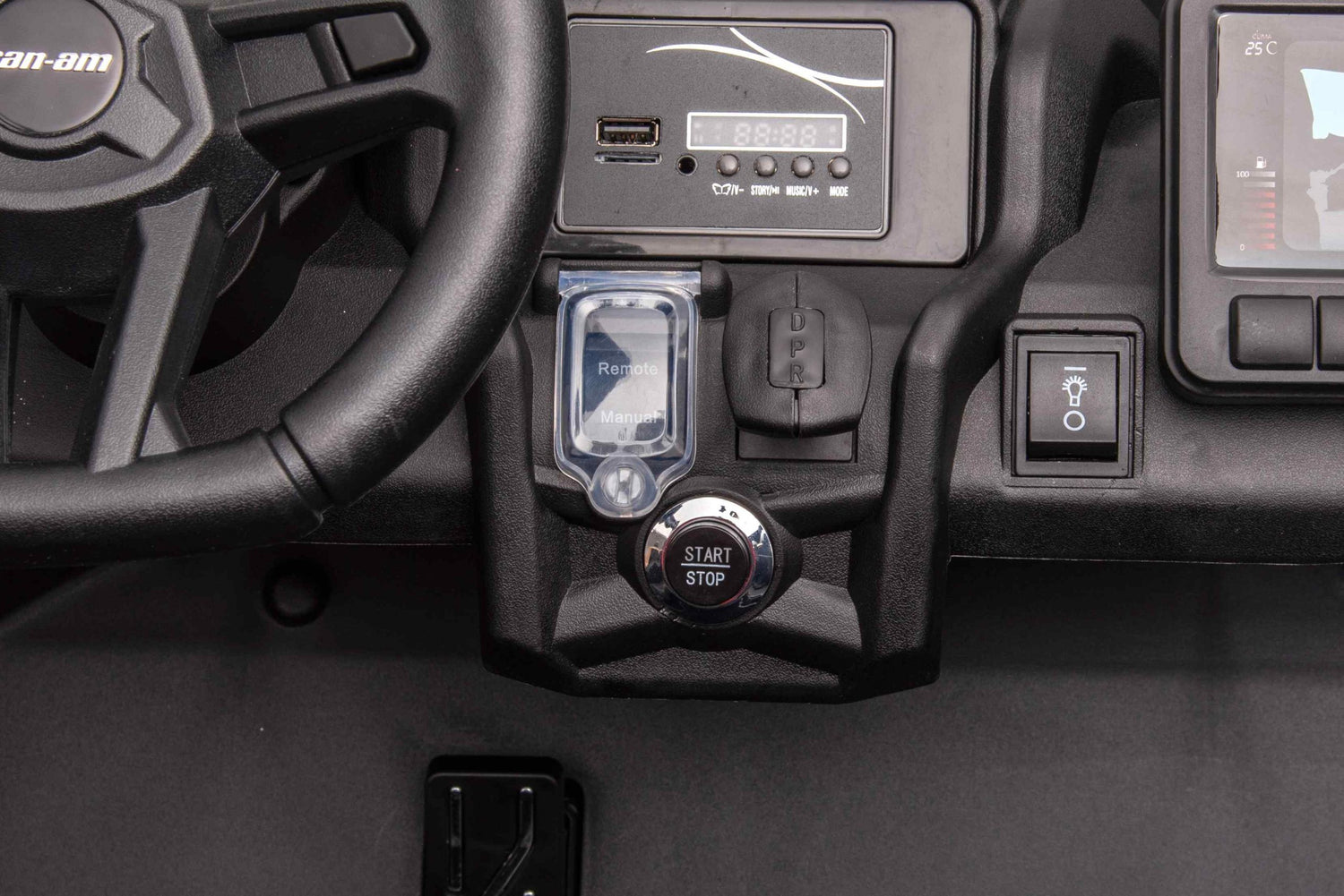 A close-up of the dashboard in the 2 Seater Official 2x24v Can-Am Maverick RS Ride on Buggy, LX Performance 4WD Edition, highlights its steering wheel, digital display, start/stop button, remote key slot, power button, and additional controls for vehicle operation.