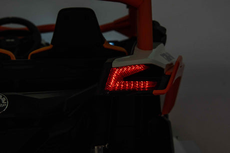 In a dim setting, the rear of the Yellow 2x24V/4WD Official Can-Am Maverick Ride on Buggy, LX Performance Edition showcases its uniquely shaped red taillight. The zigzag design stands out against the vehicles dark surroundings, exuding sleek sophistication.