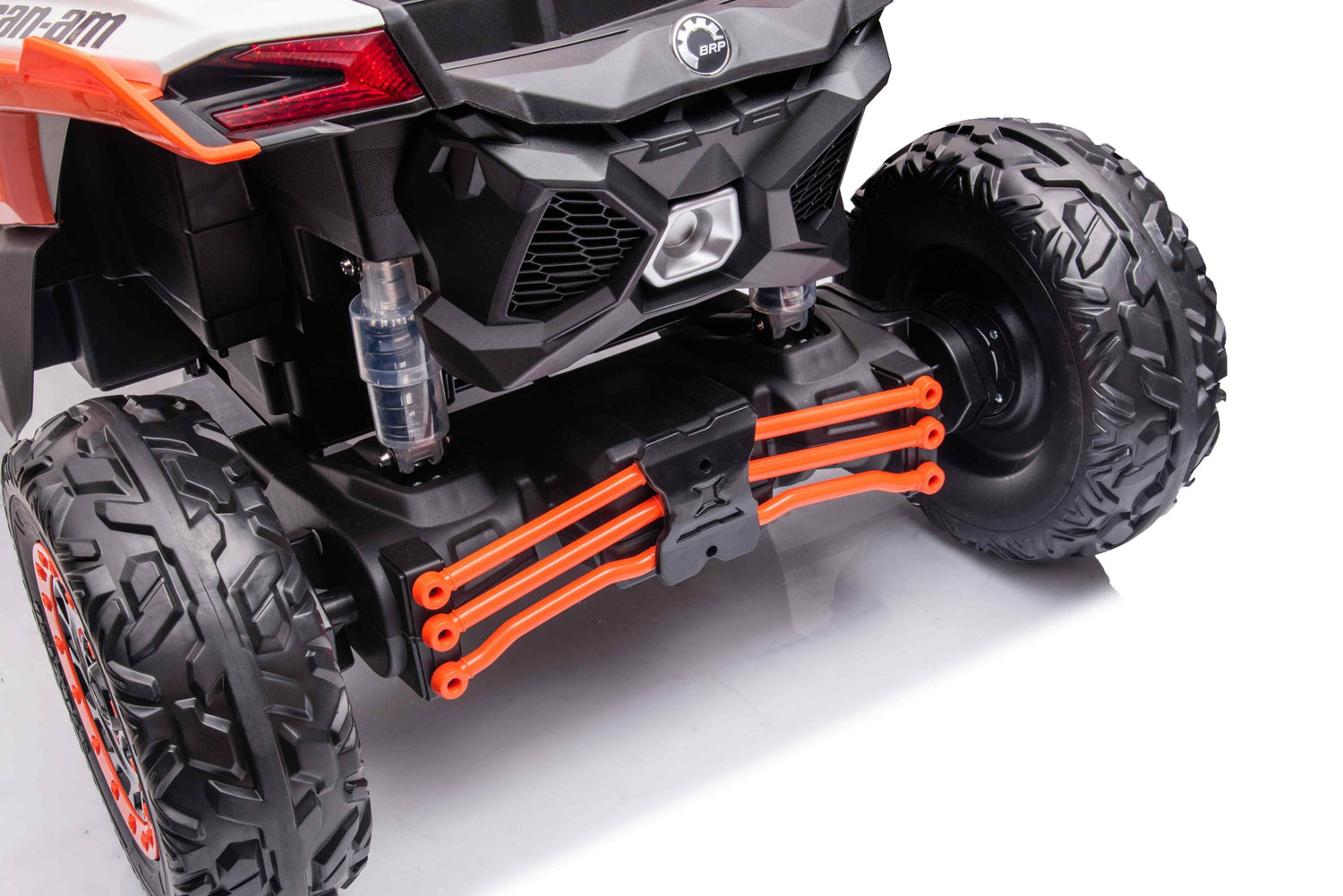 A close-up of the rear section of the Orange 2x24V/4WD Official Can-Am Maverick Ride on Buggy, LX Performance showcases its large rugged tires, black matte body with orange suspension components, and visible shock absorber. The glossy surface beautifully reflects light.