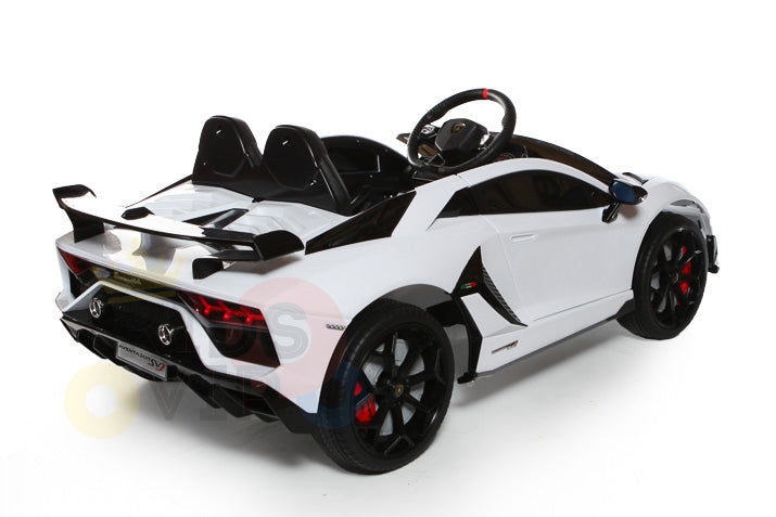 The White 12V Lamborghini SVJ Sport Kids Licensed Ride-On Car features a sleek aerodynamic design, black accents, red brake calipers, large rubber wheels, and a detailed interior. It includes a prominent rear spoiler and offers thrilling rides for young drivers with parental remote control.