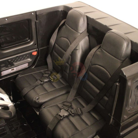The Mercedes Benz G63 Ride On Car features two black leather seats with textured patterns and seat belts, giving a sleek, modern feel in its compact interior. The black doors include handles and control panels, echoing high-end kids ride-on cars.