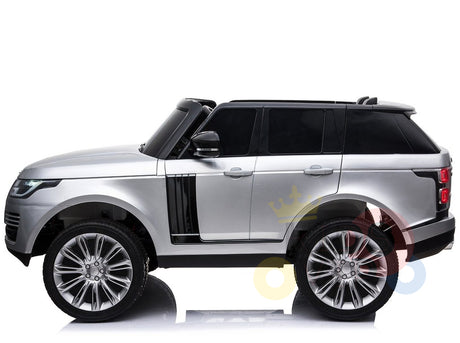 A silver 24V Complete Silver Edition Range Rover Kids Ride On Car with black accents is displayed on a white background. It has detailed wheels, tinted windows, and colorful letters partially visible in the backdrop, adding a playful touch.