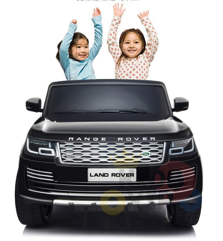 Two joyful children with raised arms stand through the sunroof of a stationary Black 24V Official Range Rover Complete MP4 Edition Kids Ride On Car with RC, centered in the image against a plain white background.