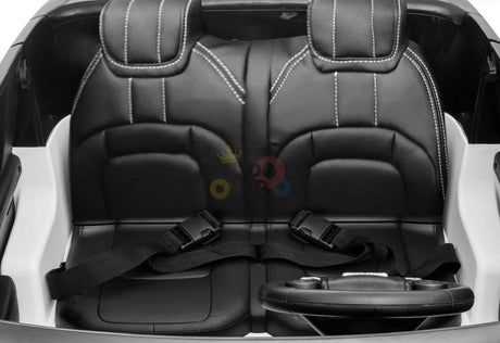 The Pink 24V Official Range Rover Complete MP4 Edition Kids Ride On Car features two black faux leather seats with white stitching, each equipped with a black seatbelt, and a small steering wheel positioned in front.