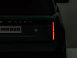 Close-up of a dark green Range Rover, focusing on the rear with license plate LRR998, a glowing right taillight, and a partially visible official logo.