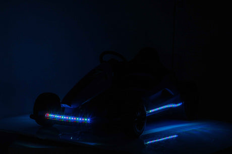 A silhouetted Pink 24V Ultra-Violent Big Kids Complete Edition Drifting Go-Kart with LED lights illuminates wheels and frame in a dim setting, perfect for high-speed drifting adventures.