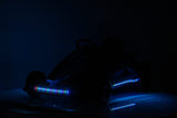 A Big Kids 24 Volt Ultra-Violent Complete Edition Drifting Go-Kart with colorful LED lights accentuating its front and sides is parked on a dark surface, with the dim backdrop enhancing its vibrant glow.