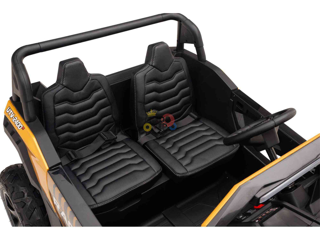 The Gold 2 Seater XXL Blade XR Edition 24V 180W Ride On Buggy UTV, designed for children, features two black seats with seat belts, a steering wheel, and an interior with molded stitching and textured surfaces for an authentic ride.