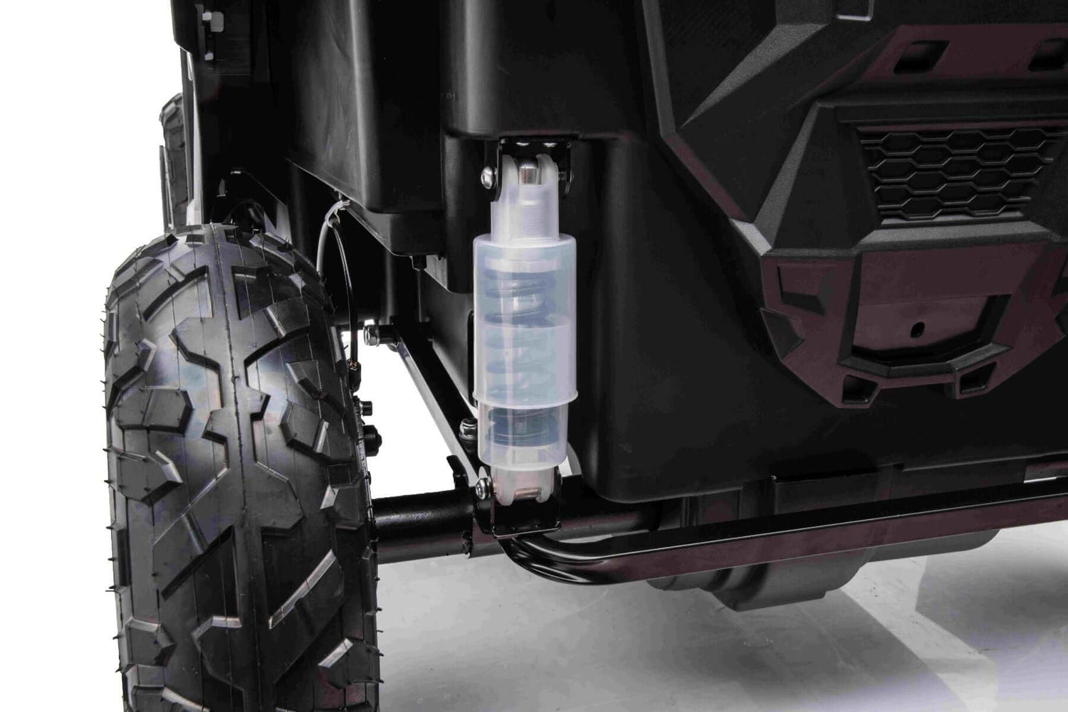 Close-up of the White 24V/180W XXL Big Kids Blade XR Ride on Buggys rugged wheel and suspension system, showcasing a transparent shock absorber, black chassis, and inflatable rubber tires for durability and exceptional off-road capabilities.