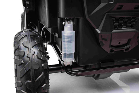 Close-up of the White 24V/180W XXL Big Kids Blade XR Ride on Buggys rugged wheel and suspension system, showcasing a transparent shock absorber, black chassis, and inflatable rubber tires for durability and exceptional off-road capabilities.