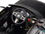 Interior view of the Black Licensed BMW GT 12V Kids Ride On Power Car with Remote Control featuring a BMW-style steering wheel, dashboard with dials and controls. The shiny surface showcases its upgraded features, including the official electric kids ride on BMW logo on the floor.
