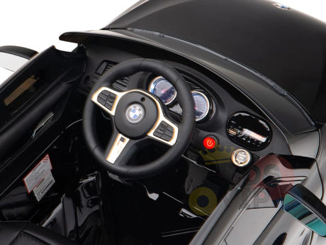 Interior view of the Black Licensed BMW GT 12V Kids Ride On Power Car with Remote Control featuring a BMW-style steering wheel, dashboard with dials and controls. The shiny surface showcases its upgraded features, including the official electric kids ride on BMW logo on the floor.
