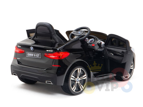 The Black Licensed BMW GT 12V Kids Ride-On Power Car with Remote Control features open doors, a steering wheel, branded detailing at the back, a detailed dashboard, shiny wheels on the side, and upgraded features.