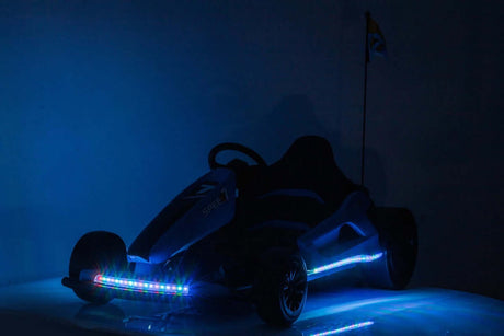 A sleek Yellow 24V Ultra-Violent Big Kids Complete Edition Drifting Go-Kart with colorful blue and red LED lights and a flag on the back. It offers precision handling with EVA-rubber wheels, all highlighted against a dimly lit background showcasing its modern design.
