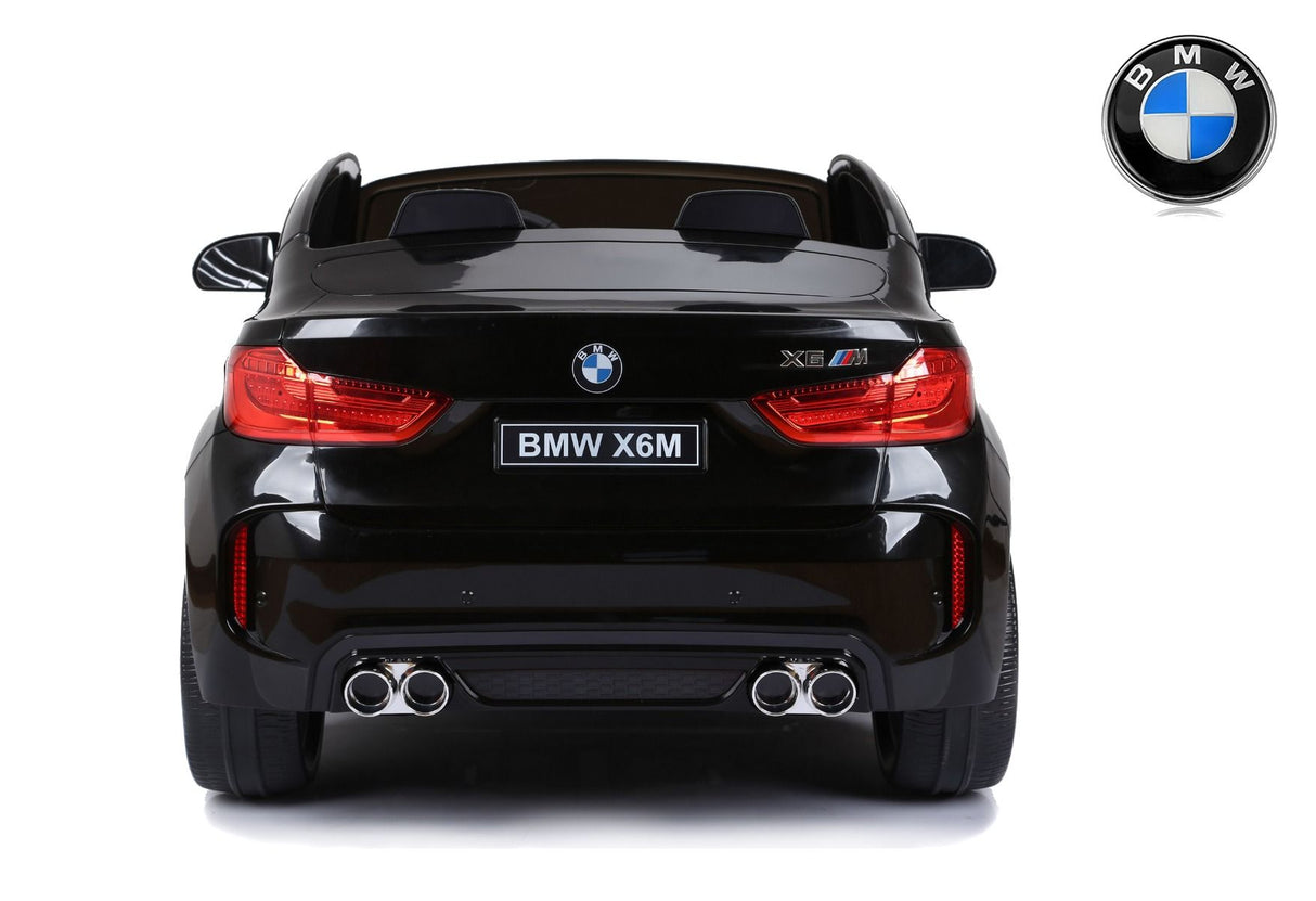 A rear view of the black 12V Licensed XXL BMW X6 Ride On Car with Remote Control shows red taillights, dual exhaust pipes, and a BMW logo on the license plate. The sleek design mimics a real BMW with its realistic details, including the iconic emblem above the car.