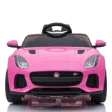 The Pink 12V Official Jaguar F Type Complete Edition Kids Ride-On Car, with detailed headlights, grill, sleek design, and a small steering wheel inside leather seats, is photographed against a plain white background from the front.