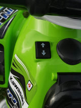 Close-up of the Green INJUSA Official 12V Kawasaki Ride On Quad for Kids, featuring two black directional buttons with arrows. Ideal for off-road fun, it sports vibrant decals and a partial Kawasaki logo on its side.