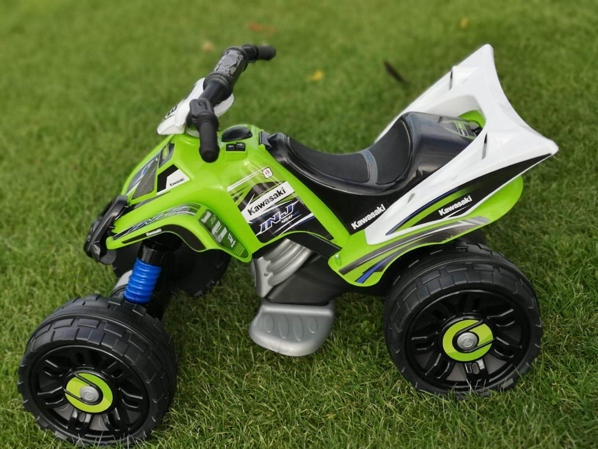 The Green INJUSA Official 12V Kawasaki Ride On Quad/ATV for Kids is on lush grass, ideal for off-road adventures with its large wheels, handlebar grips, detailed stickers, and 12V battery power.