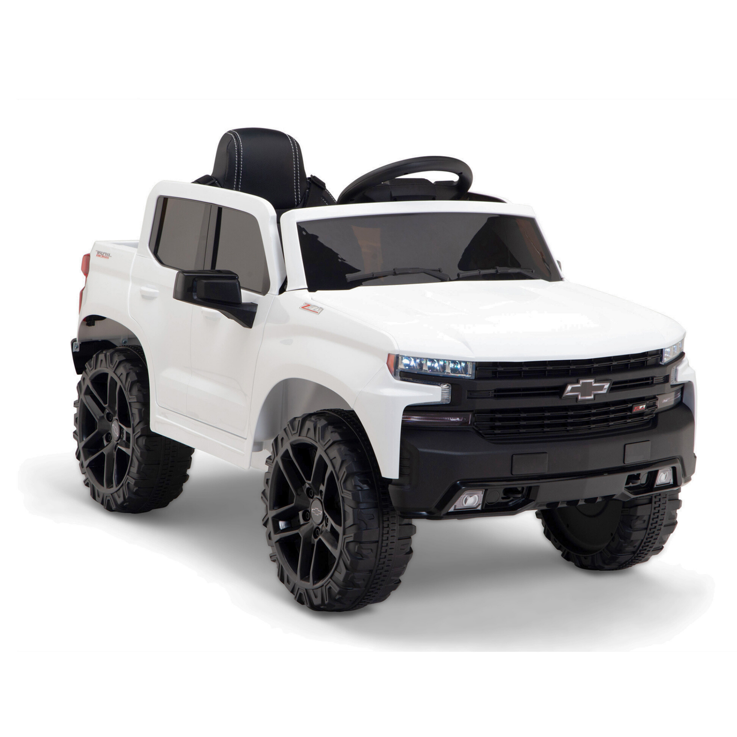 The White 12V Chevrolet Silverado Kids Licensed 1 Seater Ride On Truck with Music and Remote resembles a truck with upgraded features, including a remote control, black trim, large tires, a sleek hood with the Chevrolet logo on the grille, and a windshield revealing the steering wheel inside.