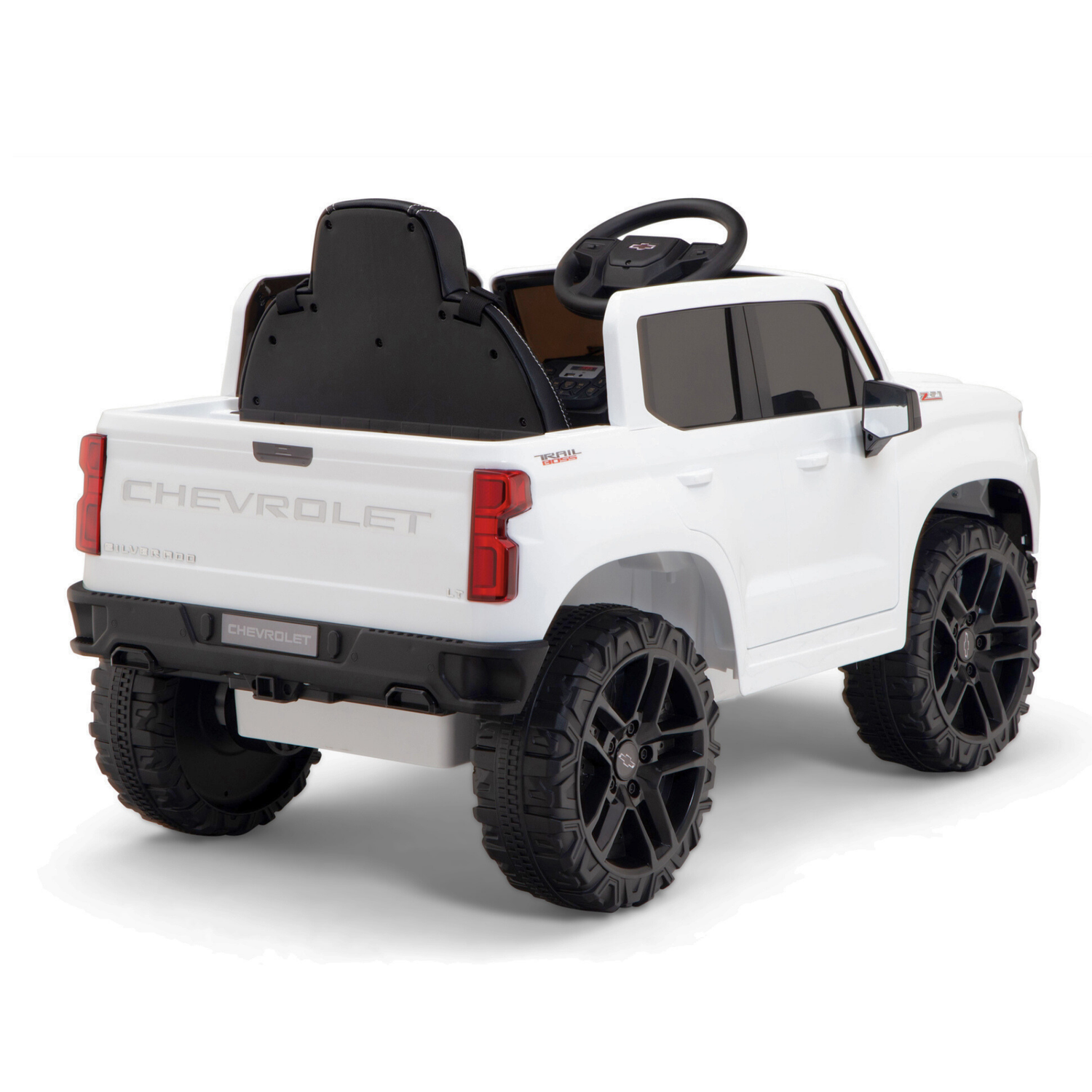 A rear view of the White 12V Chevrolet Silverado Kids Licensed 1 Seater Ride On Truck with Music, Remote shows off large black wheels, a visible steering wheel, and bold Chevrolet branding on its high back seat.