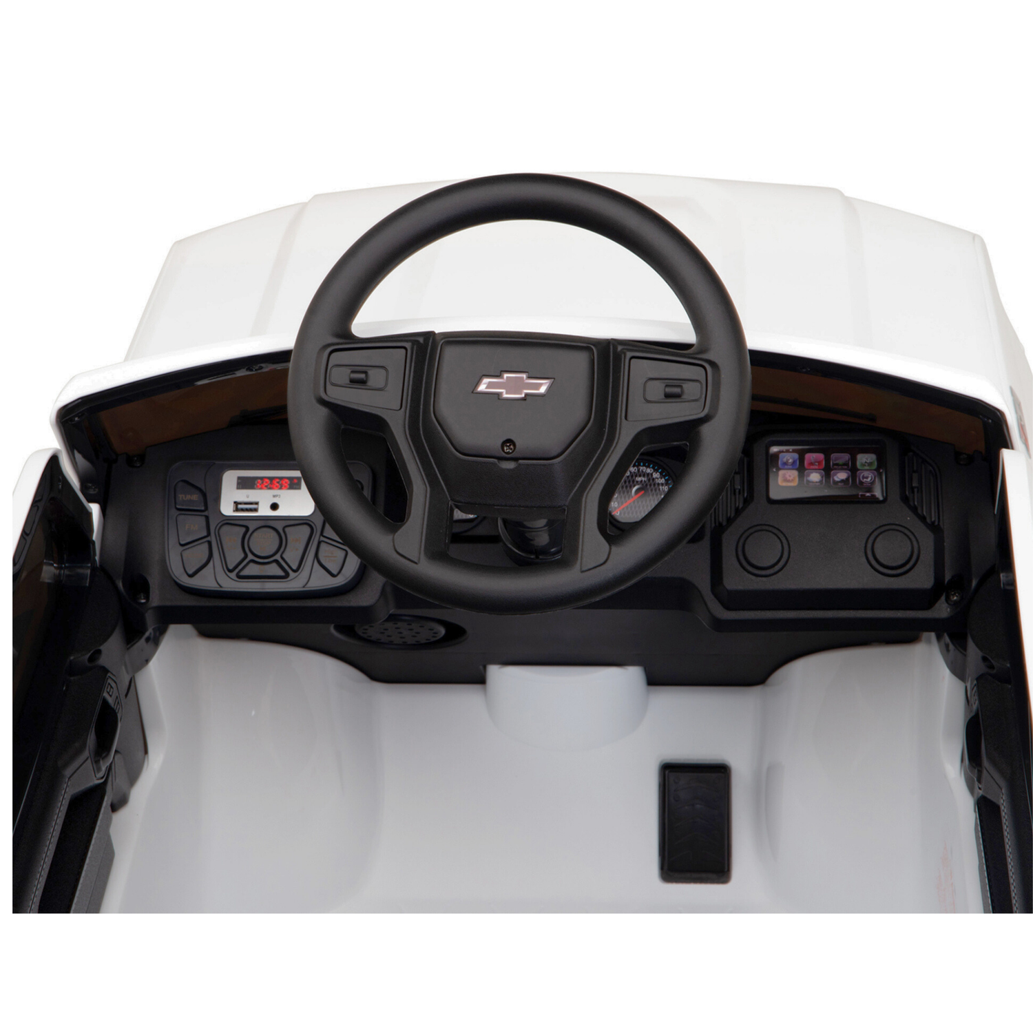 Overhead view of a toy dashboard in the White 12V Chevrolet Silverado Kids Ride On Truck, with a prominent black steering wheel and digital display reading 6:4. Styled after the real Chevrolet Silverado, it features control buttons and a central Chevrolet logo.