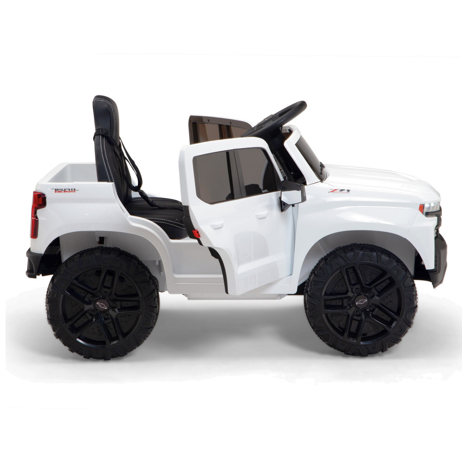 The White 12V Chevrolet Silverado Kids Licensed 1 Seater Ride On Truck features large black wheels, an open roof, a side view with a steering wheel and black seat, and includes remote control and music options to mimic an off-road vehicle.