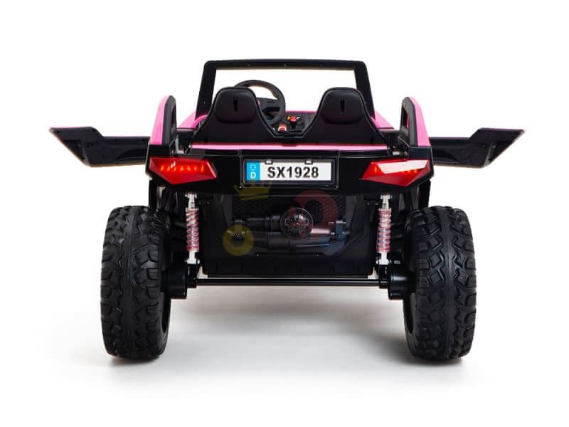 The Pink 24V/4X4 Dune Buggy Ride On UTV features a rear view in black and pink, with large rubber wheels for off-road adventures and a visible SX1928 license plate. Its two-seat design includes a raised hood and sides, enhancing its rugged style.