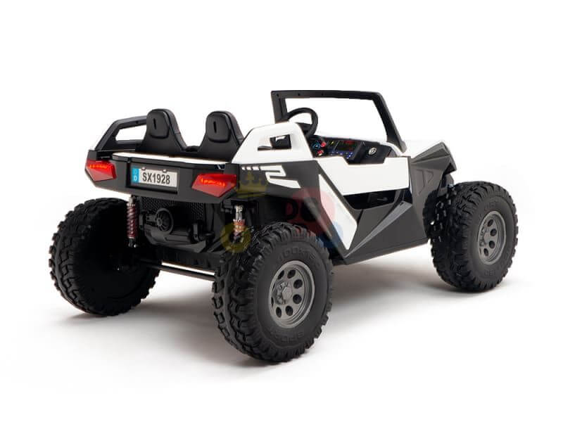 The kids XXL edition of the White 24V/4X4 Dune Buggy Ride On UTV is a child-sized, two-seater off-road toy with large rubber wheels, featuring a black and white design with red accents. A visible license plate SX1928 is shown from the rear in a studio setting.