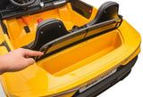 A person points at the backseat storage compartment of a yellow toy car, akin to a miniature Maserati MC20. This XXL 24V/105W ride-on features leather seats and a sleek plastic interior with black detailing, capturing the essence of luxury.