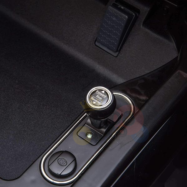 Close-up of the Black Licensed Bentley Bentayga Complete Edition 12V Kids Ride On Car with RCs electronic gear selector, featuring a round button labeled Forward, Stop, Reverse. The background highlights luxe interior details like the leather seat and a pedal near the gear selector.