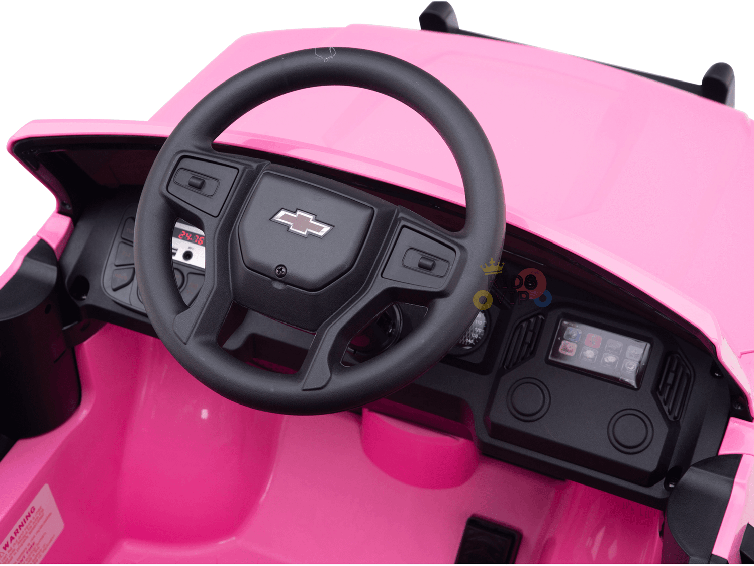 Interior view of a pink 24V Chevrolet Silverado kids ride-on lifted truck with black steering wheel and Chevrolet logo, featuring simple dashboard controls.
