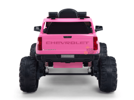 A pink 24V Chevrolet Silverado Kids Licensed 1 Seater Ride On Lifted Truck features large black tires, CHEVROLET emblems on the tailgate, and a rear-mounted spare tire, capturing adventure in a vibrant ride.